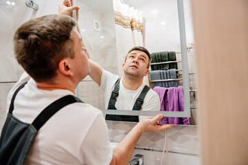 Obraz premium repairman hangs a modern electronic bathroom mirror.