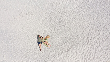 Aerial view of a young couple lying on the white sand. man and woman spend time together and travel through the desert