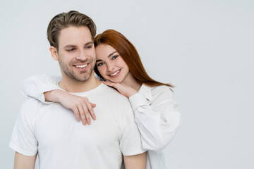 Positive young woman embracing boyfriend isolated on white.