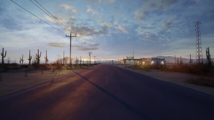 A drone flies straight over a long and empty road in the middle of the desert next Gasstation