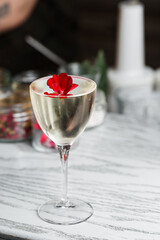 Drinking glass of daiquiri cocktail and summer flowers on wooden desk outdoors. Summer refreshing alcoholic citrus cocktail.