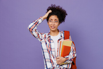 Young sad girl woman of African American ethnicity teen student in shirt backpack scratch hold head look aside isolated on plain purple background. Education in high school university college concept.