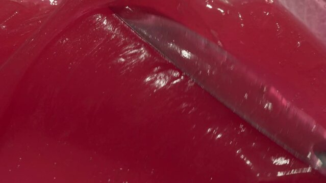 Red abstract wax cream cosmetic background video. Tooth paste texture spreading by spatula footage. Pink sticky balm, sweet toothpaste for children, gel 