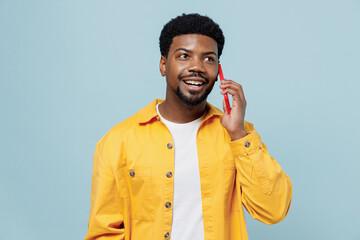 Young smiling man of African American ethnicity 20s wear yellow shirt talk speak on mobile cell...