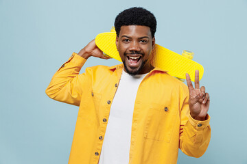 Young cool fun man of African American ethnicity 20s wear yellow shirt hold pennyboeard skateboard look camera isolated on plain pastel light blue background studio portrait. People lifestyle concept. © ViDi Studio