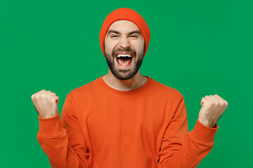 Young excited happy caucasian man 20s wear orange sweatshirt hat doing winner gesture celebrate...