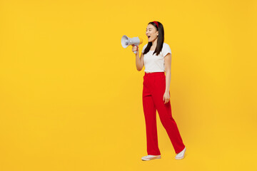 Full size body length fascinating promoter young girl woman of Asian ethnicity 20s years old wears casual clothes go move hold scream in megaphone isolated on plain yellow background studio portrait.