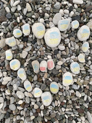Stones painted with the Ukrainian flag lies on the ground or concrete. No war. Stop the war. 
