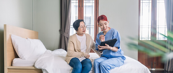 Asian woman nurse wearing scrubs report the health status of Senior Asian woman with tablet in the...