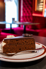 Piece of famous Sachertorte chocolate cake with apricot jam of Austrian origin served with whipped...