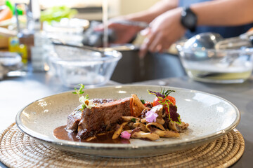 Medium Rare grilled Beef Steak with fried sliced mushroom in front of blur sink and washing glass bowl behind.