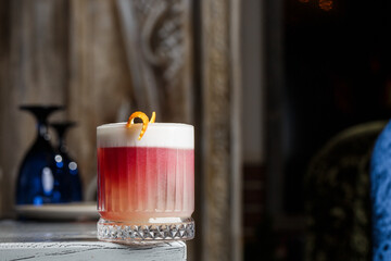Classic old fashioned red Cocktail in a retro glass with ice and orange peel on a blue background, top view
