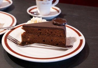 Piece of famous Sachertorte chocolate cake with apricot jam of Austrian origin served with whipped...
