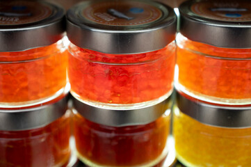 Small glass cans with real fish salmon and trout caviar for sale on fish market