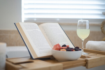 Book, fruit and champagne on a bamboo bath caddy tray