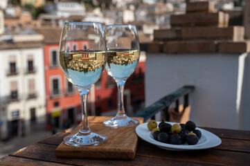 Two glasses of Spanish dry rueda white wine served on roof terrace with view on old part of Andalusian town Granada, Spain
