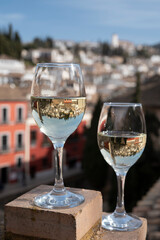 Two glasses of Spanish dry rueda white wine served on roof terrace with view on old part of Andalusian town Granada, Spain