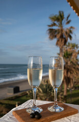 Glasses of Spanish cava sparkling wine and view on blue sea and sandy beach, Costa del Sol vacation destination, Andalusia, Spain