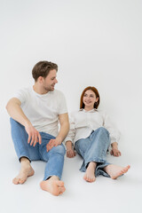 Naklejka na ściany i meble Positive barefoot couple sitting on white background.