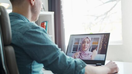 Boyfriend and his muslim girlfriend have online call conversation via internet. Young people are sitting at home and have conference call. Talking man and woman. Remote date and communication concept. - Powered by Adobe