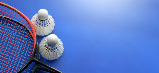 Cream white badminton shuttlecocks and racket s  on blue floor of indoor badminton court, soft and selective focus, copy space.