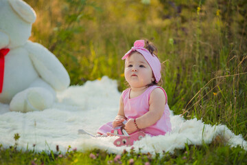 child sits next to a big teddy bear in nature