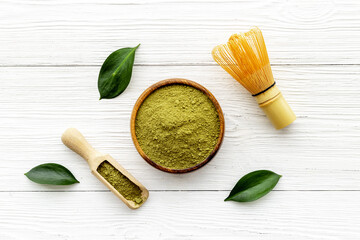 Green matcha powder in bowl with bamboo whisk