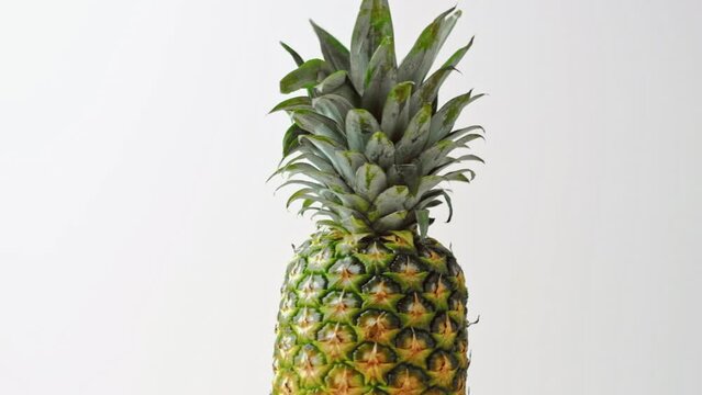 ripe pineapple rotates in slow motion on a white background. tropical summer theme