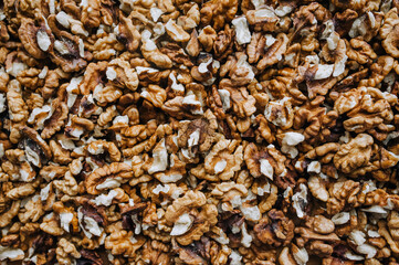 Background, texture of many brown pieces of walnuts, peeled nuts lying on the table. Food photography, top view.