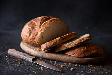 Loaf of bread freshly baked and cut on dark background