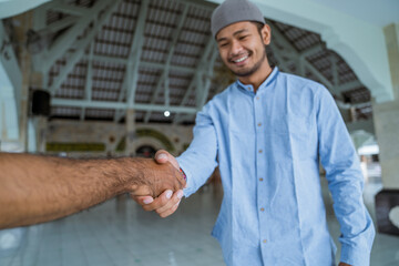 portraito of asian muslim people shaking hand at the mosque
