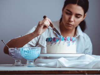 Young girl confectioner decorates homemade cake with a special spatula