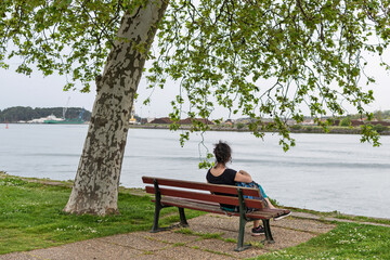 Woman sitting on the promenade of the Rio Adur. Baiona. French Basque Country
