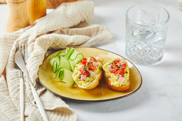 Crostini or bruschetta with softened avocado, ham and tomatoes. Toast with mashed avocado