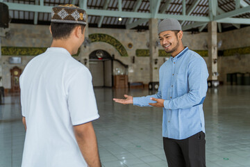 male muslim at the mosque welcoming guest to enter at the front