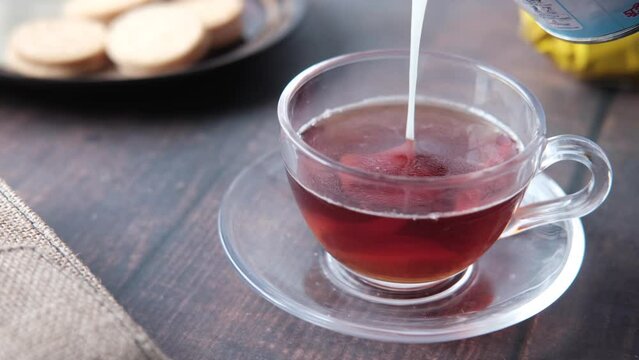 pouring condensed milk in cup of tea 