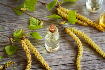 A dark bottle of essential oil with birch branches