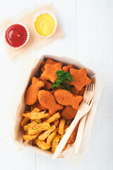 Fish and Chips british fast food. Fish Sticks with french fries set on takeaway paper plate on white wooden background. Traditional British authentic street food or takeaway food. Mock up.