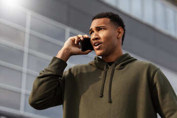 young african american man in casual outfit standing and talking on phone