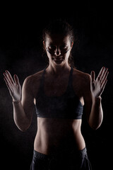 Obraz premium Kickboxer kirl with magnesium powder on her hands punching with dust visible..