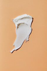 Smear of white cream in peach background. Beauty creme smear swatch. Cream, Lotion for face or body.