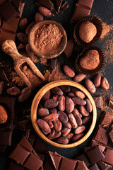 Chocolate bean cocoa. Composition of cocoa powder, bean cocoa bars and pieces of different milk and dark chocolate on black background. Baking Chocolate Texture. Top view with copy space. Mock up.