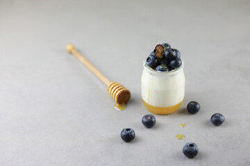 Homemade Italian dessert panna cotta with fruits jelly, fresh blue berries and honey on gray...