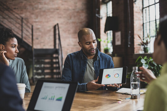 African American businessman leading a meeting using a digital tablet presentation