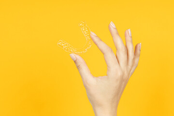 Woman hand holding Invisible tooth brackets. Dental healthcare and Orthodontic concept. Inivisalign braces or aligner