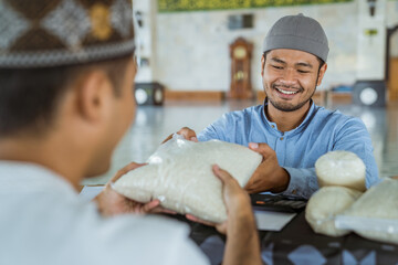 portrait of happy muslim man giving a rice as a food donation for zakat during eid mubarak at the...