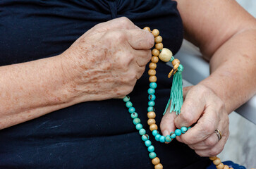 close up on senior woman hands praying with a chaplet, rosary