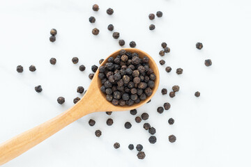 Black peppercorn with a wooden spoon on white background. Composition isolated over the white...