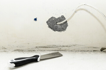 Clean spatula and wire in the wall against the backdrop of a concrete wall. Construction finishing...