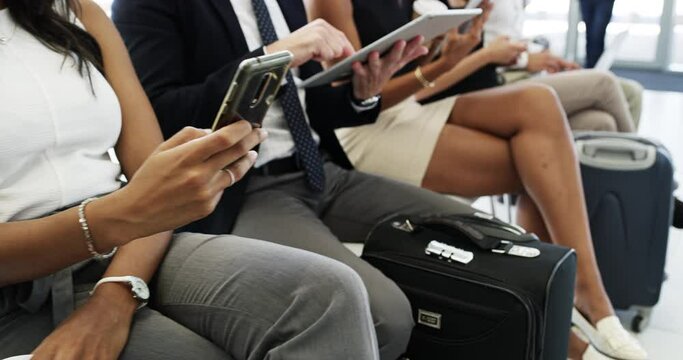 Keeping themselves occupied while they wait. group of businesspeople sitting in an airport waiting room.  Diverse businesspeople sitting in the airport using digital devices waiting to travel.